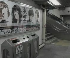 an escalator in a subway station with posters on the wall and stairs leading up to it