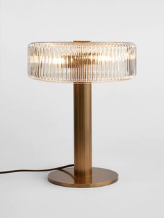 a brass table lamp with a clear glass shade on the base and a cord attached to it