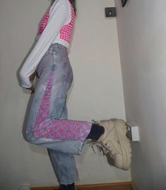 a woman is leaning against the wall with her foot in the air and looking down