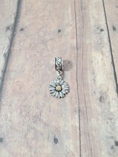 "Cute daisy pendant on European style bail. (1 sided) You will receive 1 pendant. The daisy is zinc alloy and the bail is silver plated base metal. Perfect for necklaces, charm bracelets, zipper pulls, or other crafting needs! Approximate size:  1/2\" x 2/5\" bail & 2/3\" x 1/2\" daisy pendant. Made in USA" Dainty Silver Sunflower Jewelry, Silver Flower Charms For Gifts, Silver Daisy Jewelry Gift, Silver Daisy Jewelry For Gift, Dainty Adjustable Silver Charms, Dainty Daisy Silver Jewelry, Adjustable Silver Daisy-shaped Jewelry, Adjustable Silver Daisy Jewelry, Silver Flower Charms Jewelry