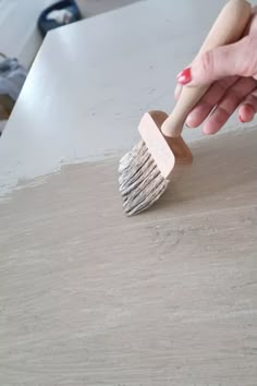 a person holding a brush on top of a wooden table