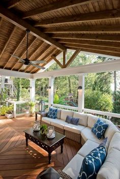 an outdoor living area with couches, tables and ceiling fans on the outside deck