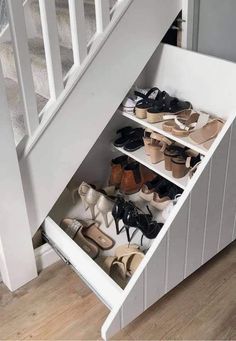 an under the stairs shoe rack with several pairs of shoes in it and one drawer open