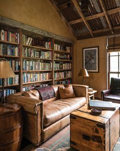 a living room filled with furniture and bookshelves next to a wooden barrel table