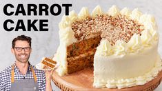 a man holding a slice of carrot cake in front of a white cake on a wooden platter