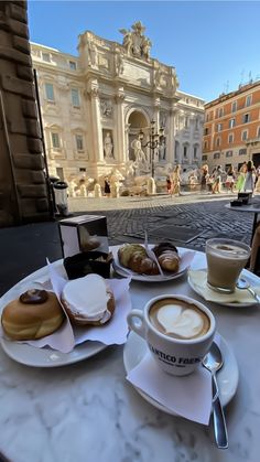 a table topped with plates of food next to a cup of cappuccino