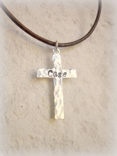 "This personalized cross necklace is perfect for that young man celebrating his First Holy Communion, Confirmation or any religious celebration or just because. This hand hammered cross necklace comes with a boy's/man's name on the front and choice of date stamped onto the back of a silver stainless steel cross. The cross measures 1\" x 5/8\". Choose from 14\"- 24\" length leather cord. Choose from black, distress brown, sun tan brown or turquoise leather cord. This necklace has a silver lobster Father's Day Gift Cross Necklace, Personalized Silver Cross Pendant Necklace, Personalized Crucifix Cross Necklace, Personalized Cross Necklace For Father's Day, Hammered Cross Necklace, Necklace Boys, Cross Necklace Mens, Confirmation Necklace, Boys First Communion