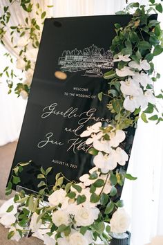 a sign with flowers and greenery on it