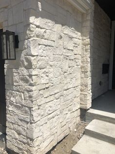 a white stone building with steps leading up to the front door and side entrance area