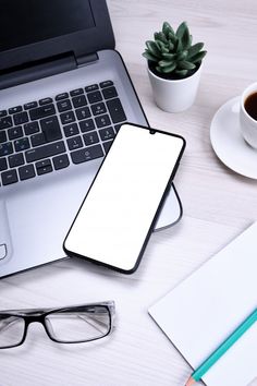 an open laptop computer sitting on top of a desk next to a cup of coffee