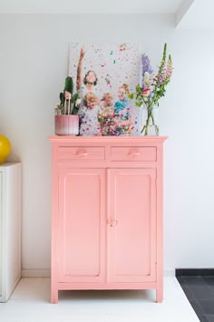 a pink dresser with some flowers on top