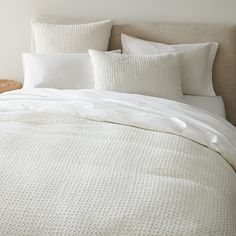 an unmade bed with white linens and pillows