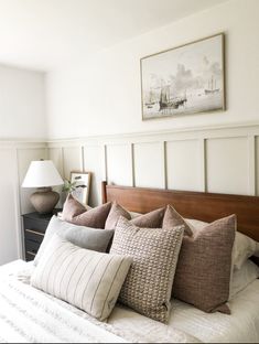 a bed with lots of pillows on it and a painting above the headboard behind it