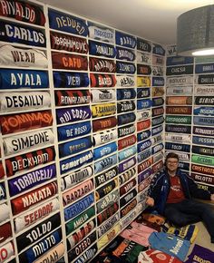 a man sitting on the floor in front of a wall full of t - shirts