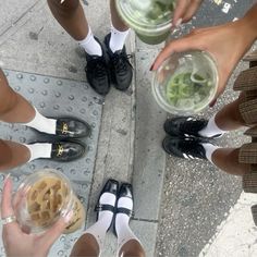 several people are standing on the sidewalk with their feet up and holding bowls of food