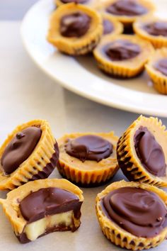 chocolate covered cupcakes sitting on top of a table next to a plate with one cut in half