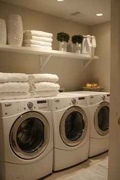 a washer and dryer in a room with towels stacked on the shelves above them