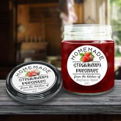 two jars of homemade strawberry preserves sitting on a table