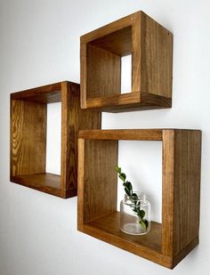 two wooden shelves with vases and plants in them hanging on the wall next to each other