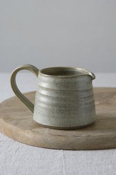 a white pitcher sitting on top of a wooden board