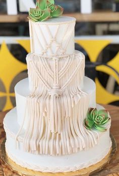 a three tiered white cake with succulents on top