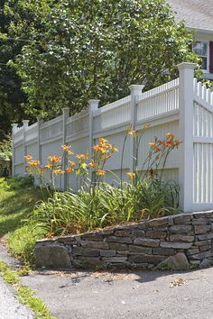 a white picket fence next to a flower bed