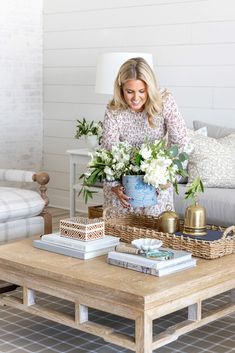 a woman arranging flowers on a coffee table