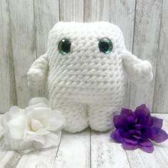 a white stuffed animal next to a purple flower