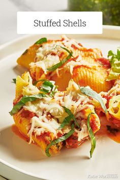 stuffed shells on a white plate with cheese and herbs in the middle, topped with tomato sauce