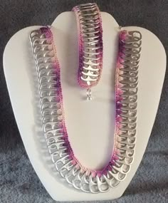 two necklaces are displayed on a white mannequin with pink and silver beads