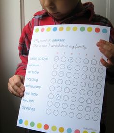 a young boy holding up a printable calendar for his family to do lists on