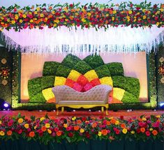 a couch covered in flowers and greenery on top of a stage