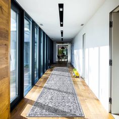 a long hallway with lots of windows and wooden flooring on either side of it