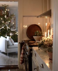 a living room with a christmas tree in the corner and candles on the counter top