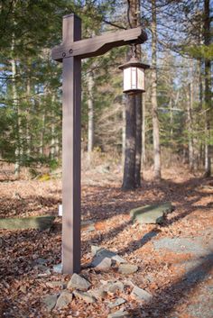 a wooden cross sitting in the middle of a forest with rocks and leaves around it