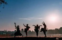 four people are dancing in front of the sun