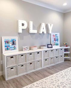 there is a play room with toy bins and pictures on the wall above it