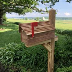 a wooden mailbox sitting on top of a lush green field