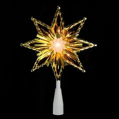 a lighted star on top of a white vase