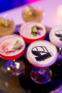 four desserts are sitting on top of a glass platter with candles in the background