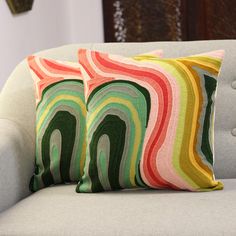 two colorful pillows sitting on top of a couch