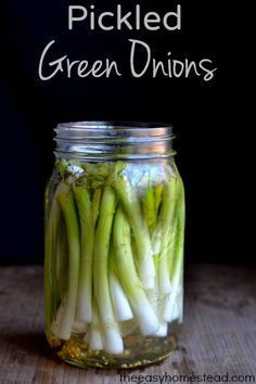 pickled green onions in a mason jar with text overlay that reads pickled green onions