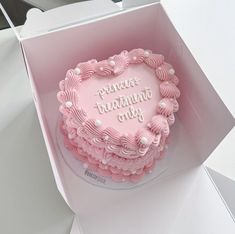 a pink heart shaped cake sitting inside of a box on top of a white table