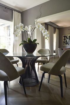 a dining room table with chairs and a vase filled with flowers on top of it