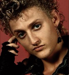 a close up of a person with curly hair holding a cell phone to his ear