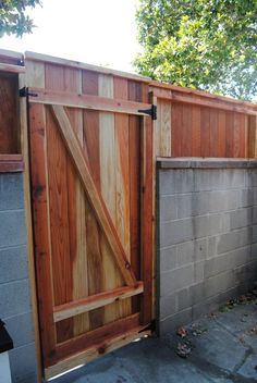 an open wooden gate in front of a brick wall