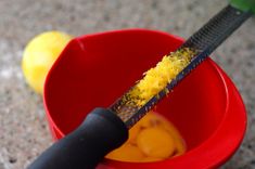 a red bowl filled with yellow food next to a black handled knife on top of it