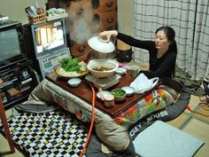 a woman sitting on the floor in front of a tv pouring tea into a pot