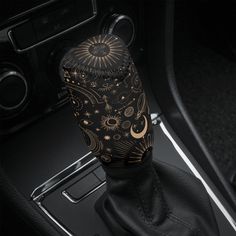 a black and gold car shift knob cover with an intricate design on the center console