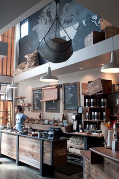 the interior of a coffee shop with lots of counter space and hanging lights above it